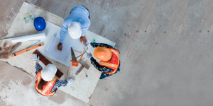 Top down photo of construction workers looking at plans around a table