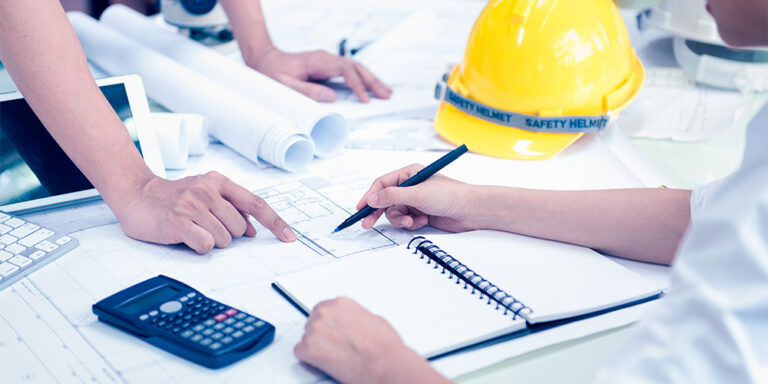 2 people looking at construction financial documents with hard hat on the table