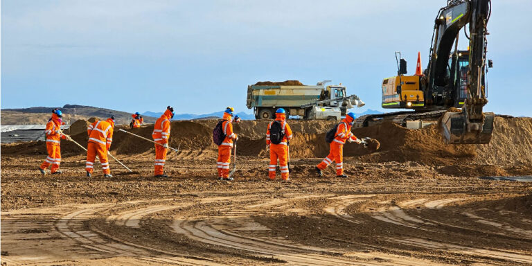 6 workers and an excavator performing earthwork construction