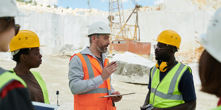 A Construction Project Manager stands in an active construction site setting out the days plans to his crew