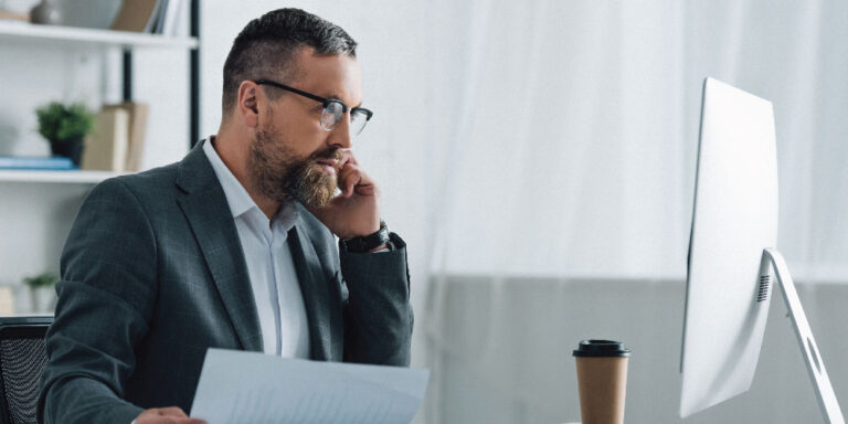 Man on the phone while looking at a desktop computer