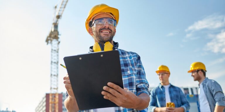 Estimator in a hard hat looking at a tablet on a jobsite