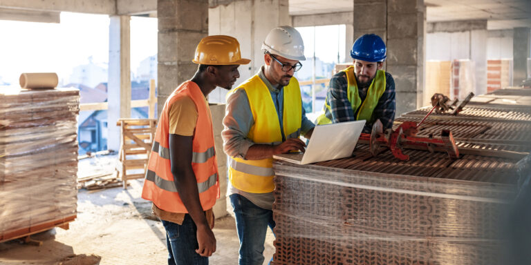 Construction cost control — workers reviewing budget documents on a laptop