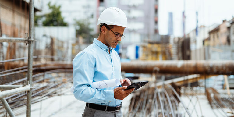 Professional performing construction data analysis on tablet with a jobsite in the background