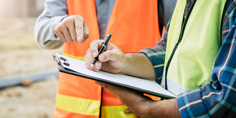 2 people reviewing a rough-in inspection checklist on a clipboard