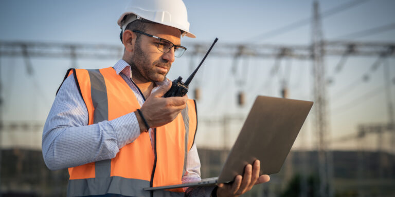 Engineer using construction tech with electronic tablet and walkie-talkie