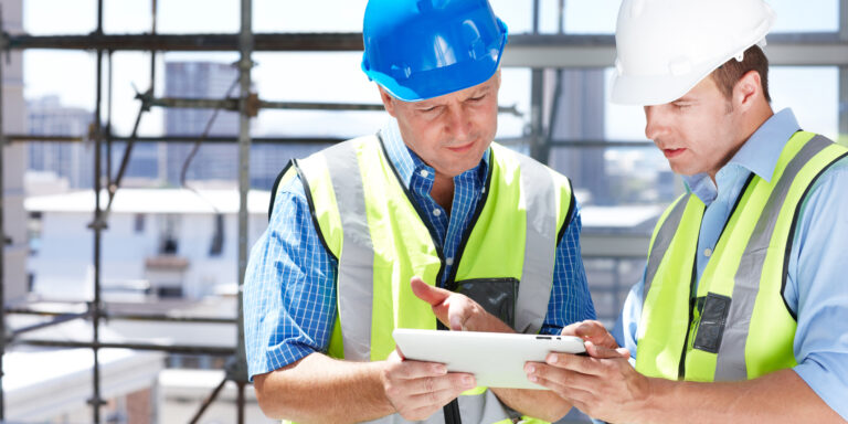 Two construction workers looking at a tablet