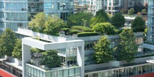 A modern looking white and glass building is covered in foliage, including on mid-level terraces, and an extensive rooftop garden