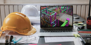 BIM manager's desk with PPE, drawings, and a laptop with a BIM model