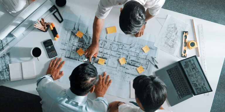 Top down photo of 3 construction professionals looking at a construction project phasing chart