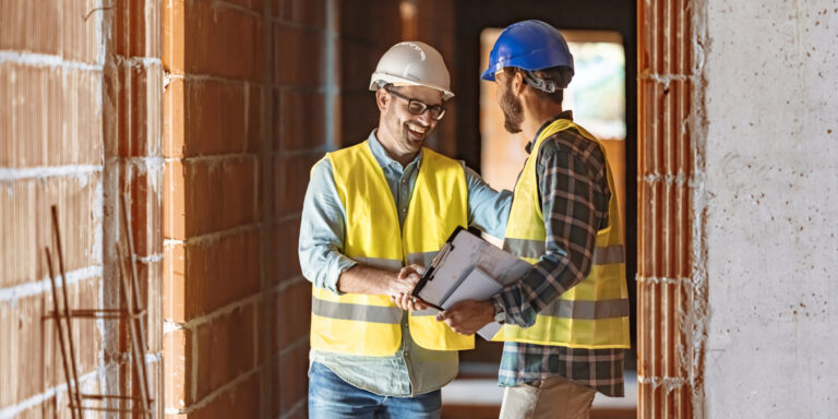 Worker and architect shaking hands at construction site after discussion around an RFQ for project materials.