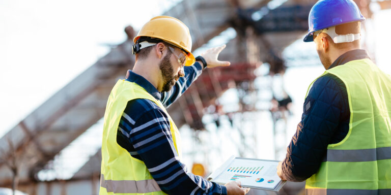 Workers on a construction jobsite looking at key metrics on a tablet