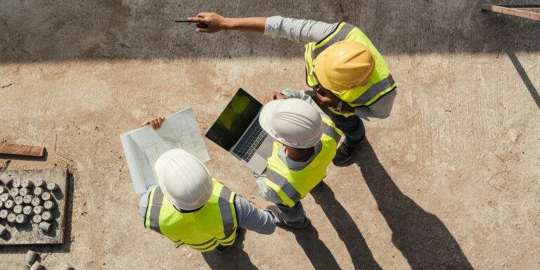 Aerial photo of 3 workers looking at construction plans on a jobsite