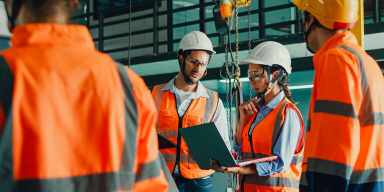 Workers on a jobsite reviewing safety protocol on a laptop