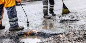 2 members of a road crew conducting pothole repair