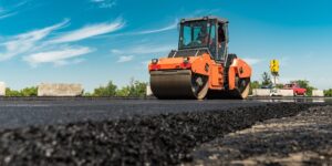 Road materials types showcased in photo of new asphalt being rolled